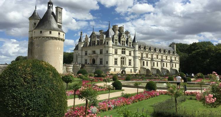 Elegante Château de Chenonceau atravesando el río, enmarcado por vibrantes jardines de rosas y arbustos recortados.