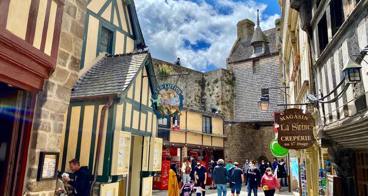 Narrow medieval street of Mont Saint-Michel lined with half-timbered shops bustling with tourists.