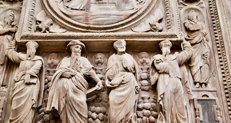 Detail of ornate stone relief carvings depicting historic religious figures on a French cathedral façade.