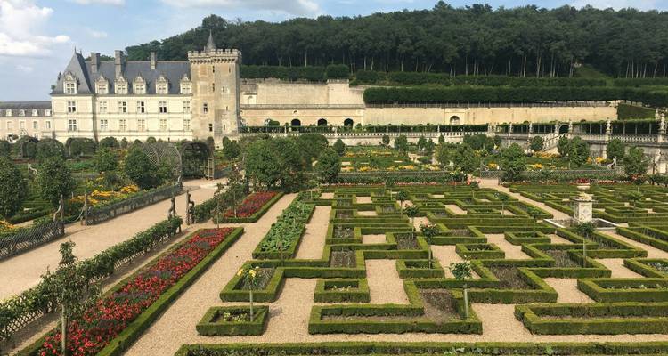 Immaculate box-hedge ornamental gardens and château of Villandry framed by forested hills.