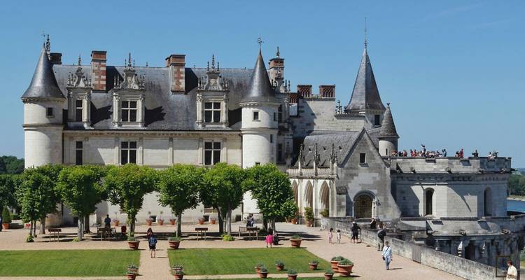 La façade en pierre grise du Château d'Amboise et ses tourelles pointues dominant les terrasses et les visiteurs par une journée ensoleillée.
