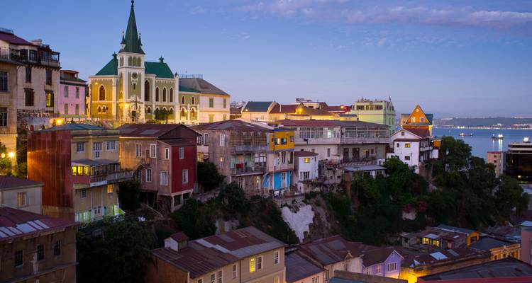 Kleurrijke huizen op de heuvelhelling van Valparaíso gloeien in het zachte avondlicht met uitzicht op de Stille Oceaan.