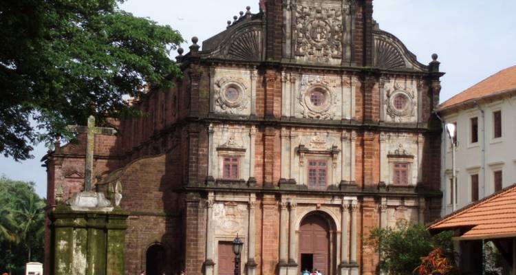 Historische rote Laterit-Basilika Bom Jesus mit barocker Fassade, umgeben von Grün.