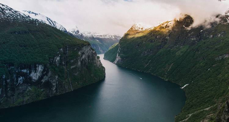 Vue aérienne spectaculaire surplombant le Geirangerfjord sinueux encadré par des falaises escarpées couvertes de forêts