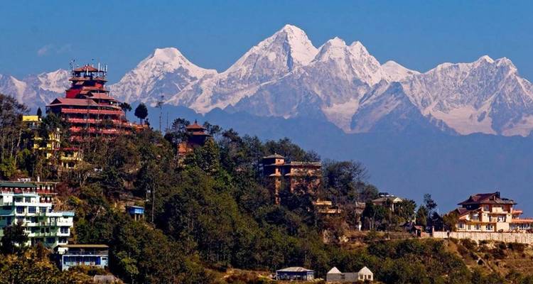 Les sommets himalayens enneigés se dressent au-dessus des contreforts boisés et de la ville à flanc de colline dans une lumière cristalline.
