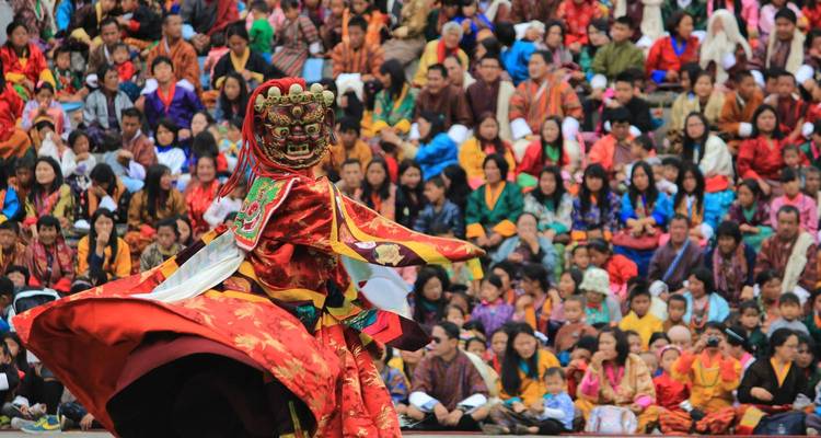 Danseur masqué vibrant tournoie devant un public comble lors d'un festival traditionnel coloré.