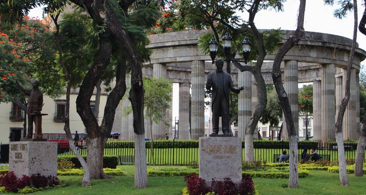 Monument rotonde en pierre entouré de statues et d'un parc verdoyant luxuriant.