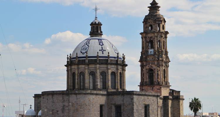 Église historique en pierre avec dôme carrelé à motifs bleu et blanc et haut clocher.