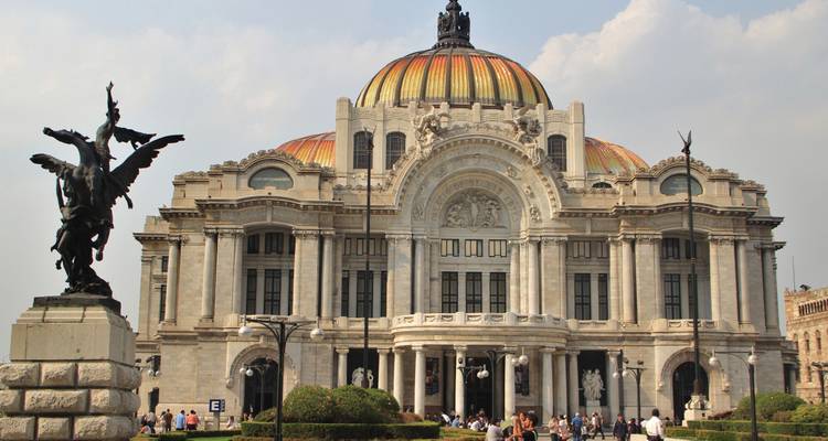 Impressive Palacio de Bellas Artes with its colorful domed roof and ornate façade, bustling with visitors in the plaza