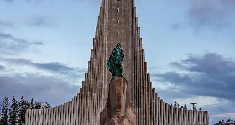 Front view of Hallgrímskirkja with Leif Erikson statue under dramatic clouds.