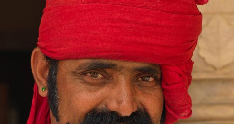 Portrait en gros plan d'un homme moustachu portant un turban rouge vif.