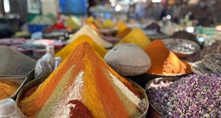 Bunte Pyramiden aus Gewürzen und getrockneten Blumen, hoch gestapelt in einem geschäftigen Souk.