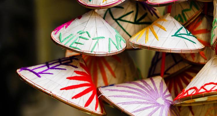 Pile de chapeaux coniques vietnamiens brodés colorés en exposition.