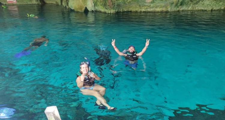 Les plongeurs avec tuba font des signes de paix en flottant dans les eaux bleues cristallines d'un cénote souterrain.