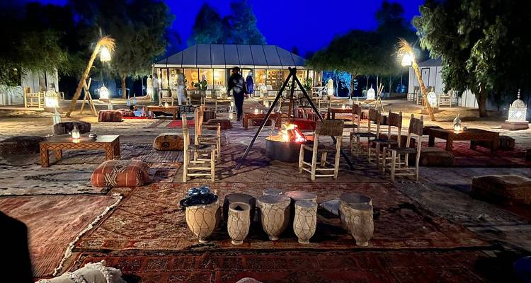 Atmosphärisches Wüstencamp bei Nacht mit zentralem Lagerfeuer, Laternen und traditionellen Sitzgelegenheiten