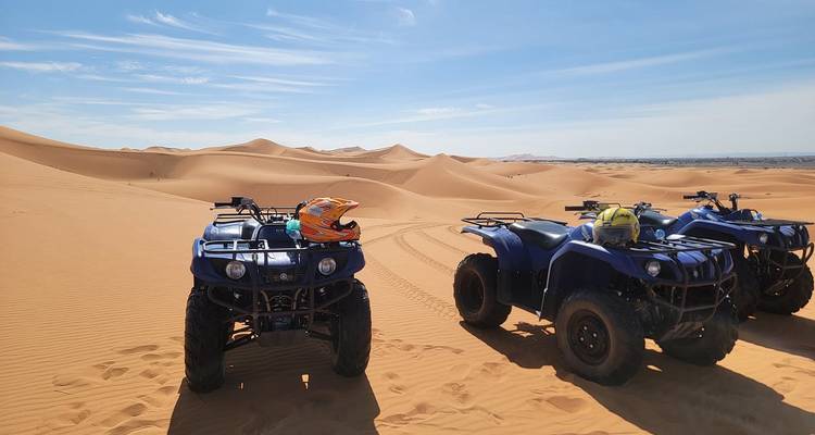 Blaue Quads geparkt auf weiten, welligen orangefarbenen Sanddünen unter klarem Himmel