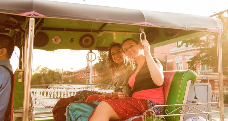 Deux voyageurs roulent dans un tuk-tuk à ciel ouvert en souriant sous la douce lumière de l'après-midi.
