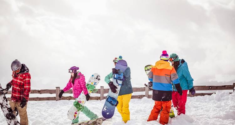 Snowboarders in kleurrijke uitrusting die zich voorbereiden om te rijden op een poederachtige berghelling