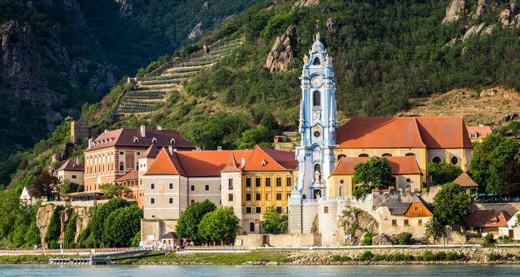 Der blau-weiße Barockturm der Stiftskirche Dürnstein erhebt sich über das Donauufer.