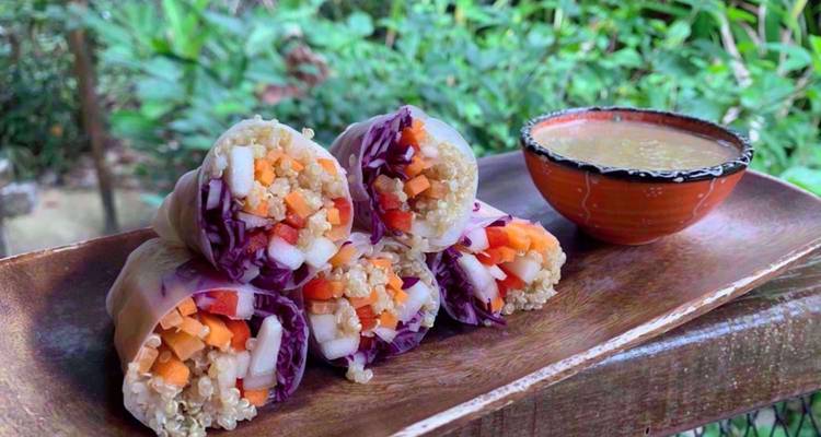 Close-up van kleurrijke verse groente loempia's netjes gestapeld op een houten schaal met dipsaus.