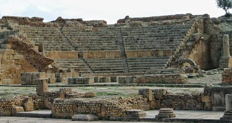 Anfiteatro romano antiguo con asientos de piedra desgastada y muros parciales en Argelia.