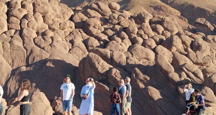 Voyageurs se tenant parmi les formations rocheuses désertiques arrondies sous le soleil de fin d'après-midi