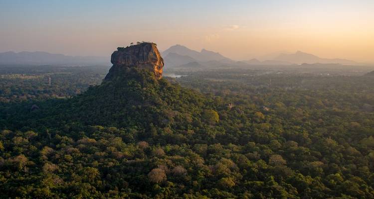 Vue aérienne spectaculaire du rocher de Sigirîya s'élevant au-dessus de la jungle dense au lever du soleil doré.