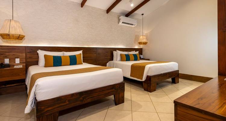 Modernes Hotelzimmer mit zwei Doppelbetten, Holzmöbeln und warmem Ambientelicht.