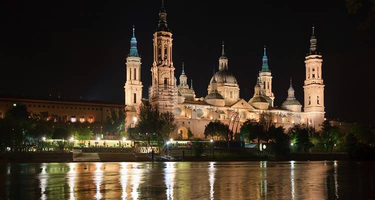 La Basilique de Notre-Dame du Pilier magnifiquement illuminée la nuit se reflète dans l'Èbre.
