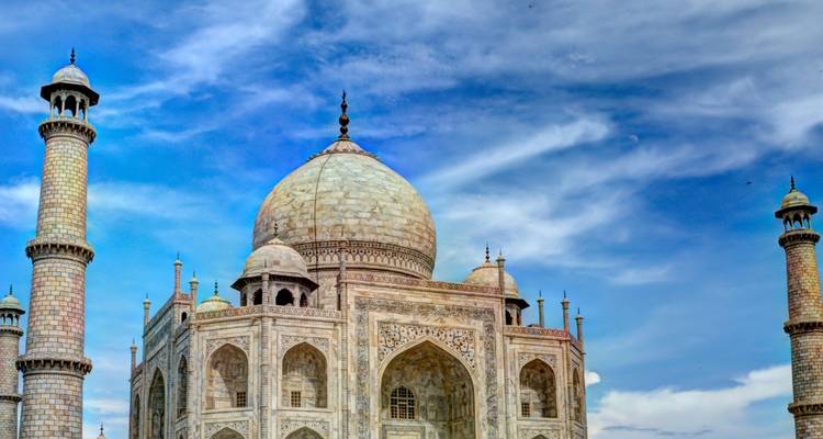 De iconische marmeren koepel en minaretten van de Taj Mahal rijzen op tegen een levendige blauwe hemel.