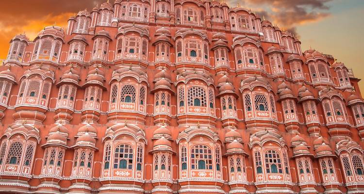 De sierlijke honingraatgevel van Jaipur's Hawa Mahal gloeit warm onder een dramatische zonsonderganghemel.