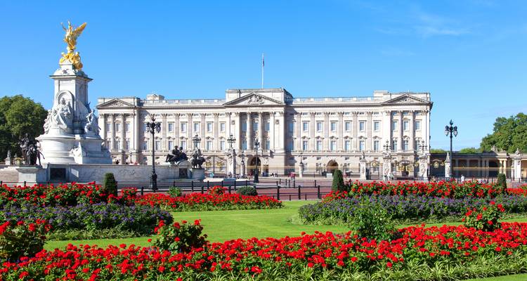 Vue de face du palais de Buckingham avec des parterres de fleurs colorés et le mémorial Victoria par une journée d'un bleu éclatant