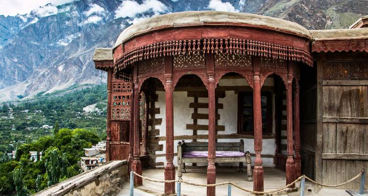 Historic wooden terrace of Baltit Fort overlooking green Hunza valley.