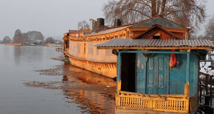 Péniche traditionnelle en bois amarrée sur un lac calme au crépuscule avec des reflets et des arbres d'hiver dénudés