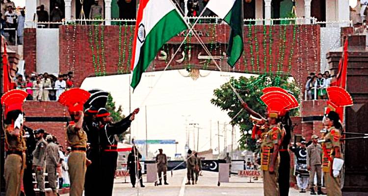 Ceremonial guards from two nations performing the Wagah border flag-lowering ceremony with large crowds watching.