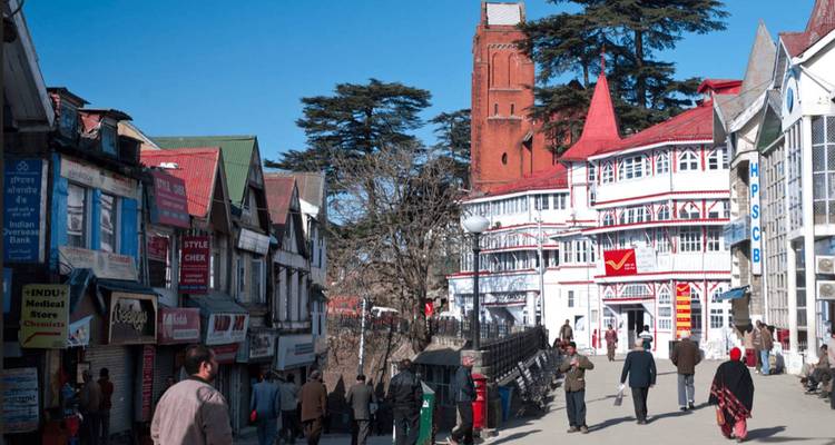Bustling colonial street in Shimla lined with colourful shops and historic buildings under a clear blue sky.