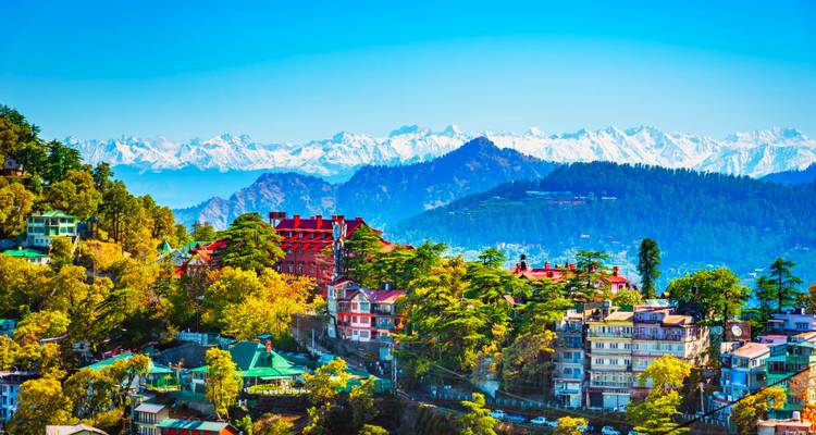 Vibrant panoramic view of Shimla town spread across forested hills with distant snow-clad Himalayas.