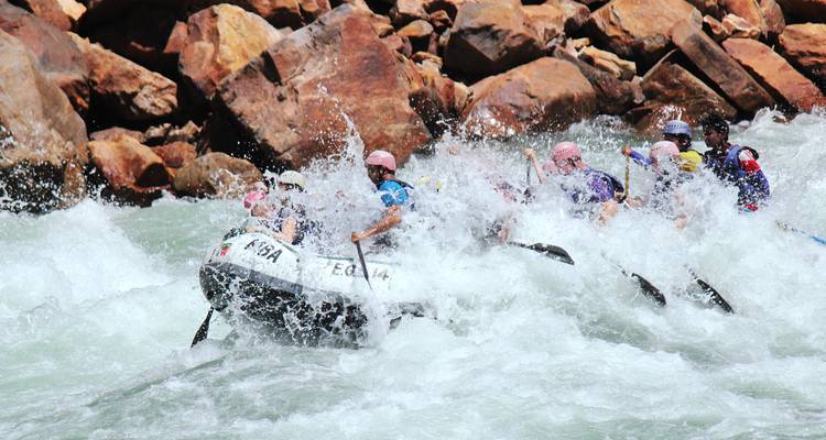 Thrill-seekers white-water rafting through powerful rapids with splashing waves all around.
