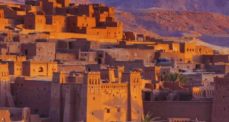 Goldene Stunde Blick auf das befestigte Lehmdorf Ait Benhaddou vor zerklüfteten Hügeln.