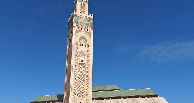 La gran Mezquita Hassan II con su minarete ornamentado se alza junto a un cielo azul profundo en Casablanca.