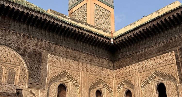 Aufwendig geschnitzter Innenhof und Minarett einer historischen Madrasa mit kunstvollen geometrischen Fliesen