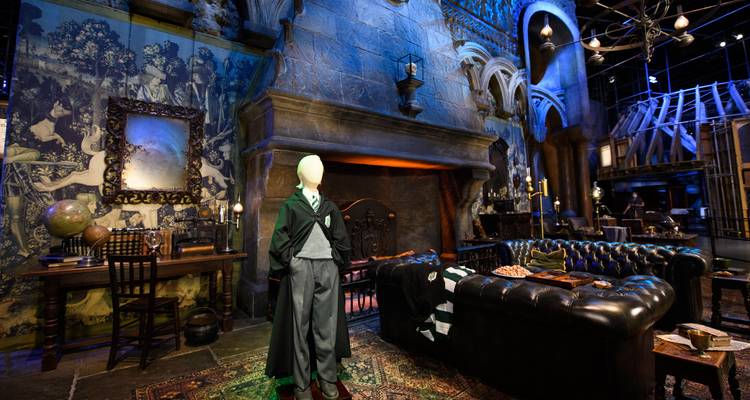 Décor atmosphérique des studios Harry Potter avec cheminée gothique, tapisseries et mannequin en uniforme scolaire.