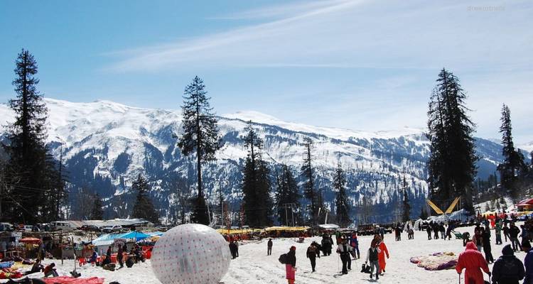 Schneebedecktes Tal voller Touristen, die vor der Kulisse der verschneiten Himalaya-Gebirgsketten Wintersport betreiben