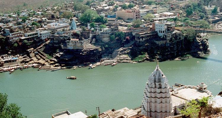 Luftaufnahme der Stadt Maheshwar, die auf Klippen über dem grünen Narmada-Fluss thront.