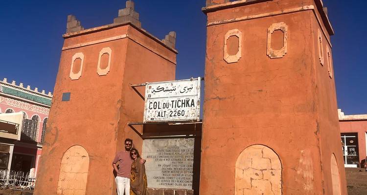 Des voyageurs posent devant les tours jumelles couleur rouille marquant le sommet du Col du Tichka à 2260 m d'altitude.