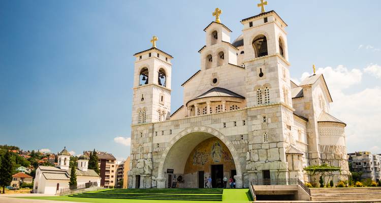 Helle Ansicht der weißsteinernen Kathedrale der Auferstehung Christi mit goldenen Kreuzen vor blauem Himmel.
