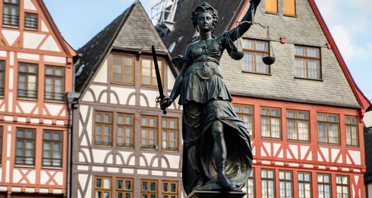 Statue der Justitia vor Fachwerkhäusern auf dem Römerberg in Frankfurt.