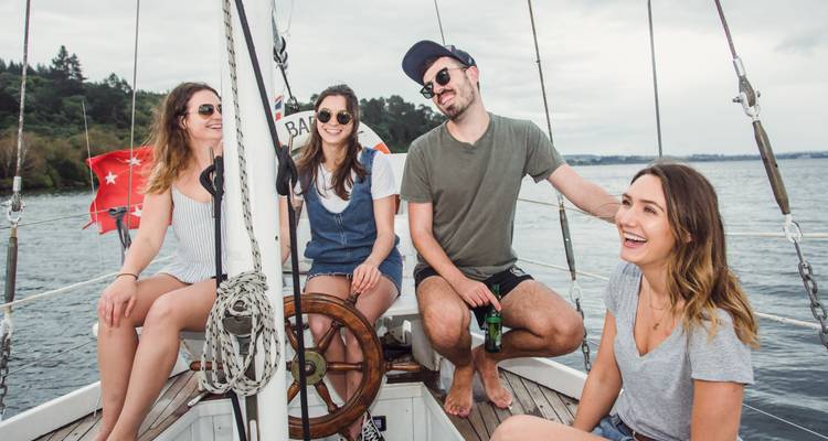 Des amis se détendant et riant en naviguant sur un petit bateau avec un drapeau rouge qui flotte.