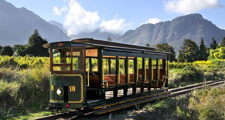 Vintage open-air tram set among vineyards with mountain backdrop