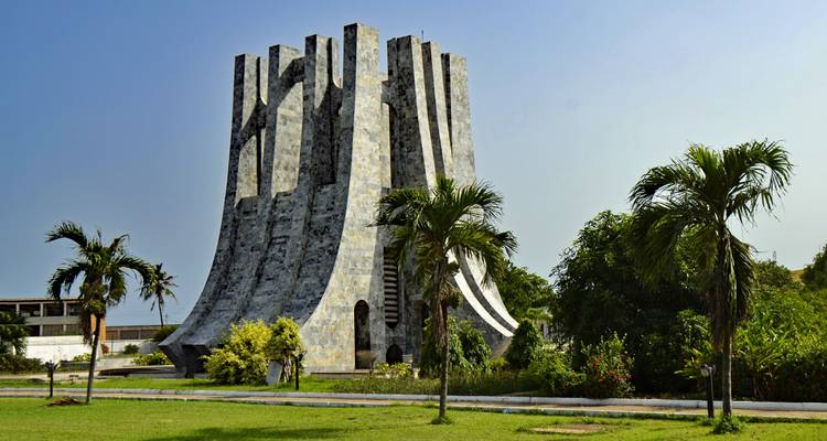 Markante modernistische Steinmausoleum-Struktur inmitten gepflegter Rasenflächen und Palmen in Accra.
